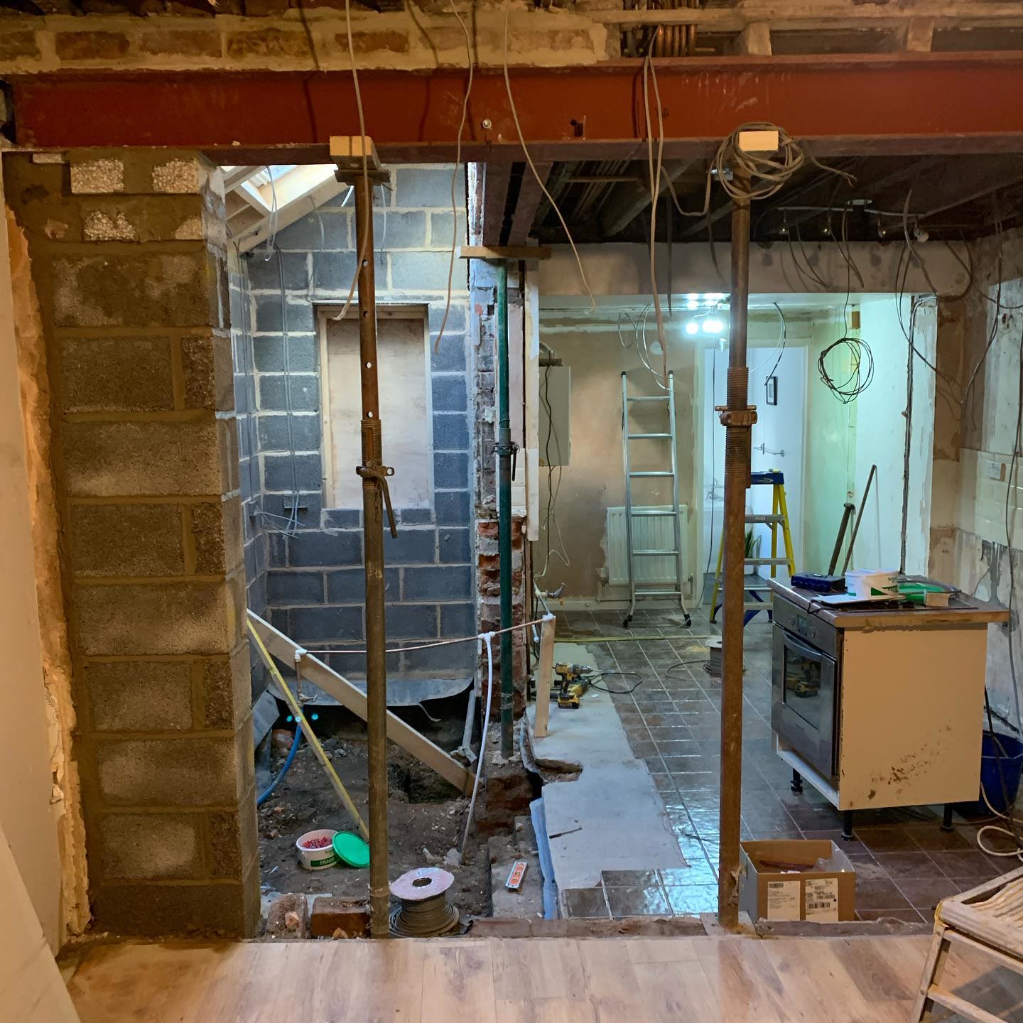 Kitchen stripped back during renovation, with acrow props, a steel beam and first-fix cable runs in place