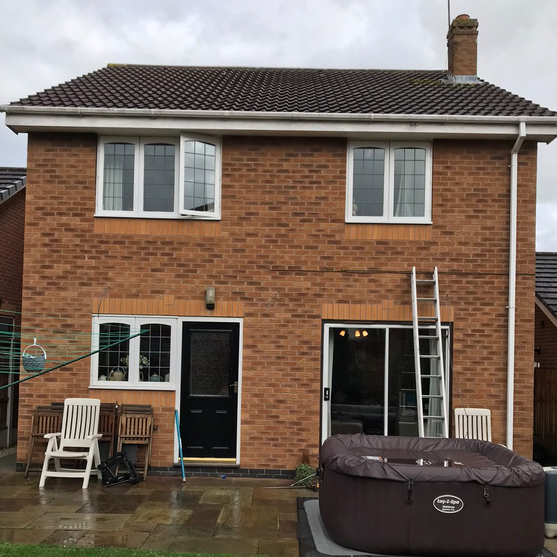 The back of the house before the work, in daylight, with bare brickwork above the patio doors and no exterior lighting fitted