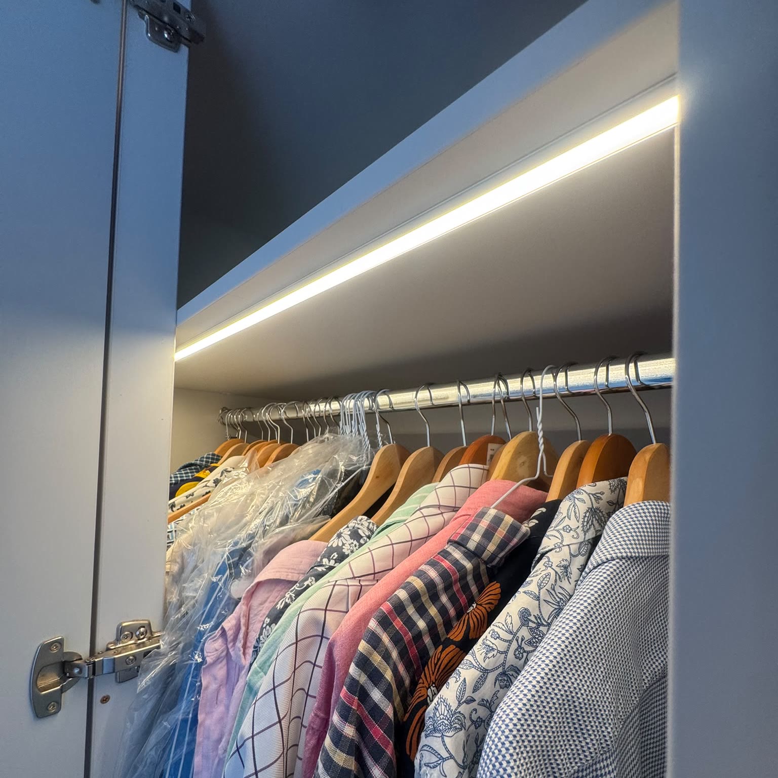 LED strip lighting fitted along the inside of a fitted wardrobe, lighting the rail below