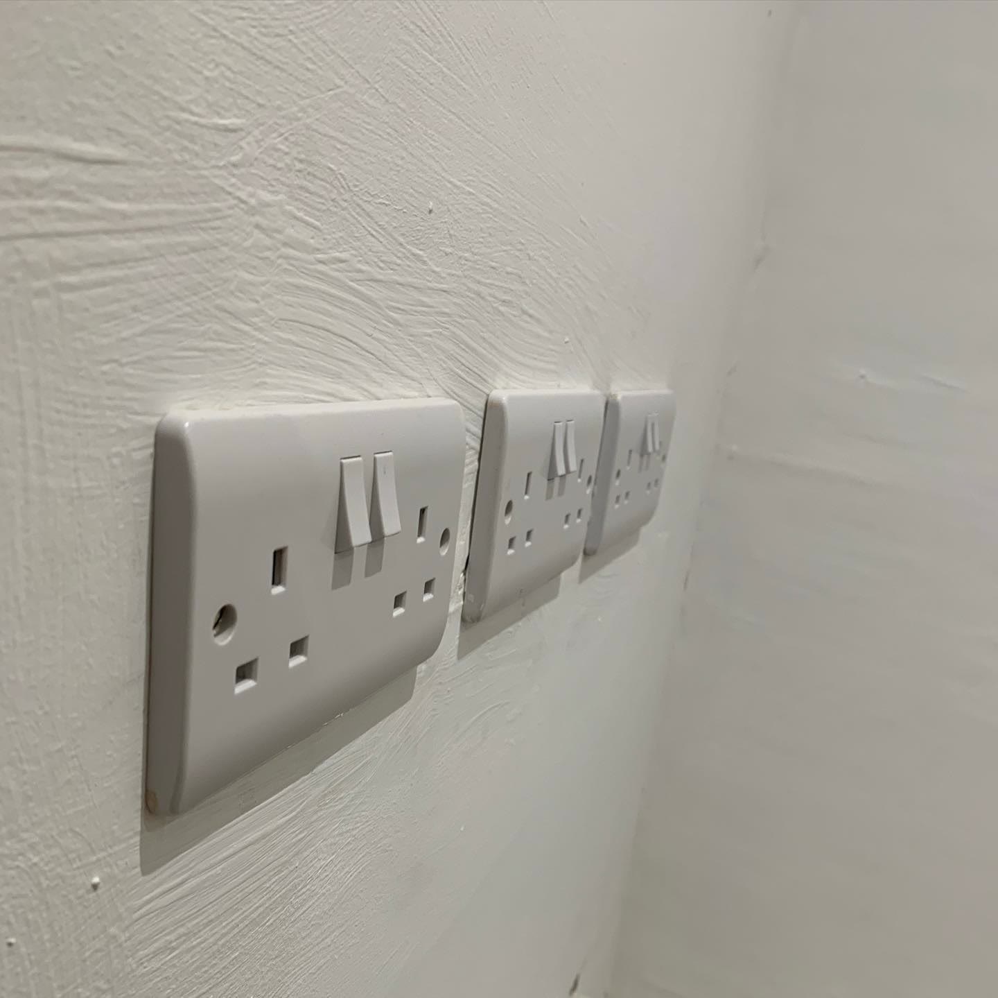 Bank of three double sockets installed in a line along a freshly painted wall
