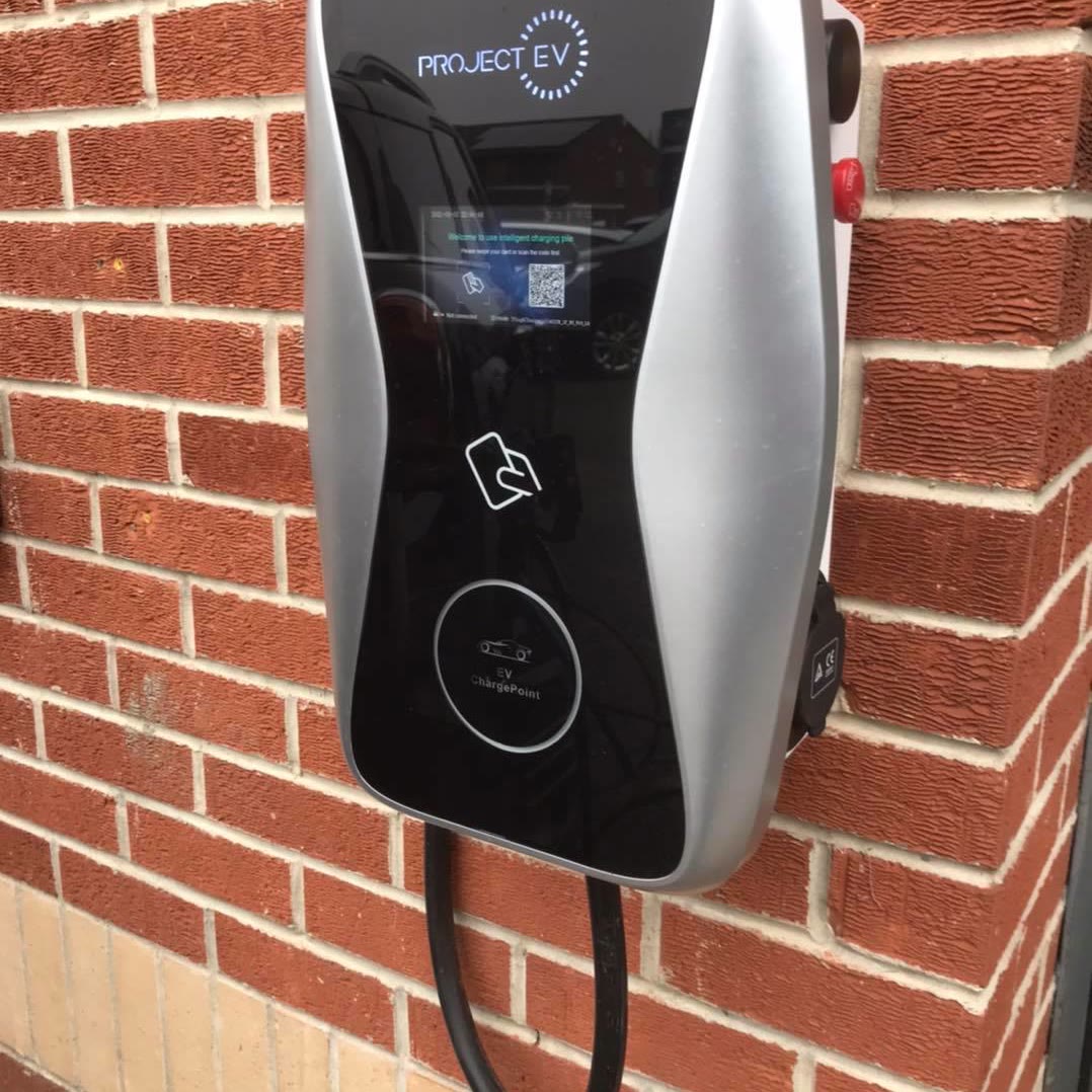 Wall-mounted electric car charge point installed on the brickwork of a house